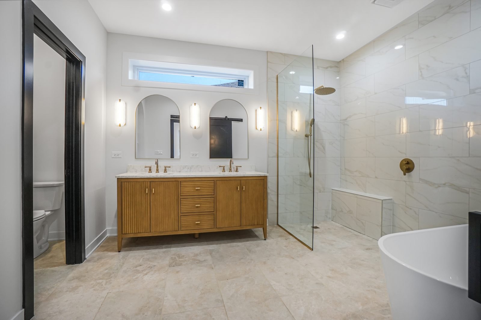 A Pensacola Avenue primary bath we finished: fluted vanity, arched mirrors and a marble wet area
